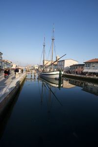 Sailboats moored in harbor against clear blue sky