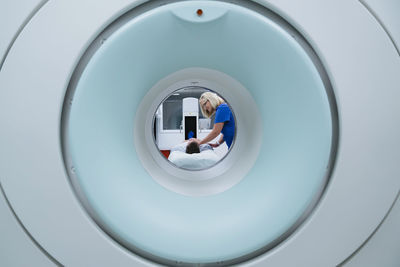 Nurse preparing patient for mri scan in hospital seen through scanner