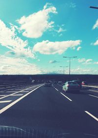 Cars on road against cloudy sky