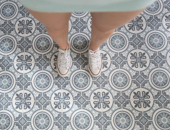 Low section of woman wearing canvas shoes while standing on floor