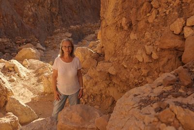 Portrait of senior woman standing against rock formation