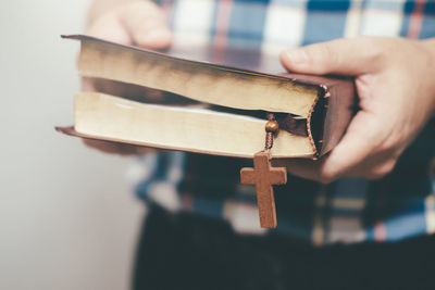 Midsection of man holding bible with cross