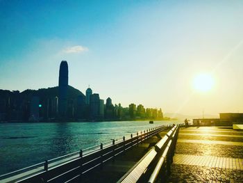 View of river by buildings against sky during sunset