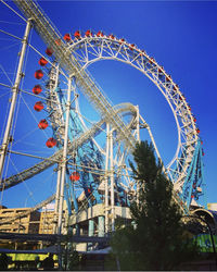 Low angle view of ferris wheel against blue sky