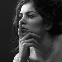 Close-up of thoughtful woman against black background