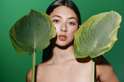 Portrait of young woman holding leaf