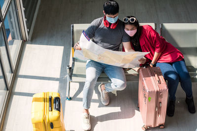 High angle view of couple looking at map while relaxing on airport