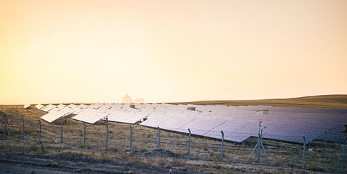 Fence on field against clear sky during sunset