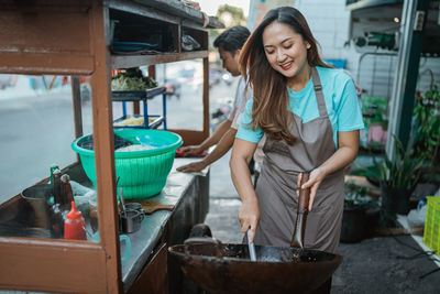 Portrait of young woman preparing food in kitchen