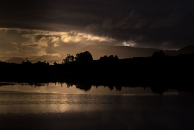 Silhouette trees by lake against sky during sunset