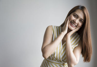 Portrait of a smiling young woman against gray background