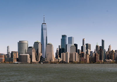 Sea by modern buildings against clear sky