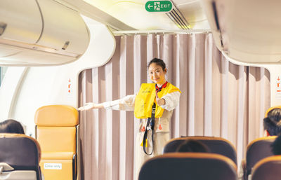 Prior to the flight's takeoff, an air hostess presents safety procedures to passengers.