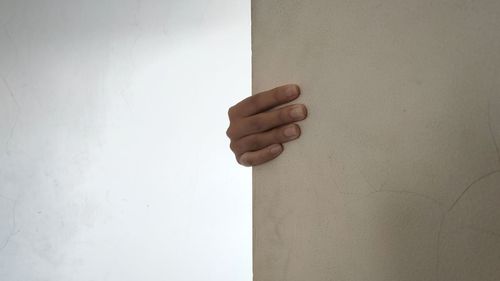 Close-up of hand against white wall