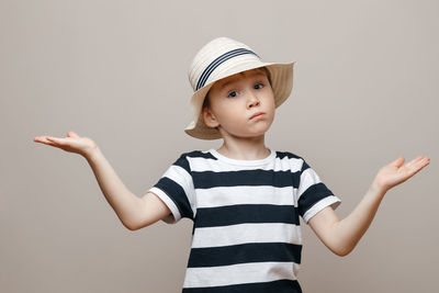 Boy looking away while standing against gray background