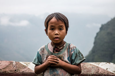 Portrait of boy standing against sky