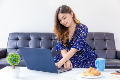 Young woman using phone while sitting on sofa