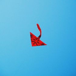 Low angle view of red kite flying against clear blue sky