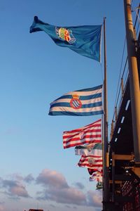 Low angle view of various flags against blue sky