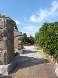 Footpath by stone wall against sky