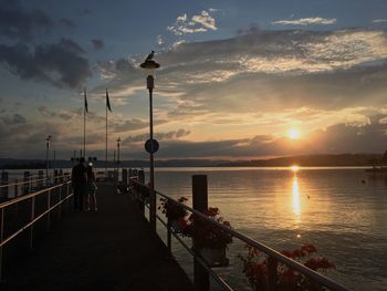 Silhouette of people on sea against sky during sunset