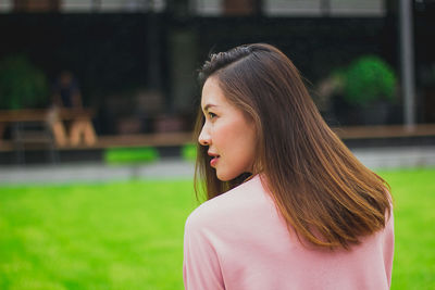 Close-up of beautiful woman looking away on field