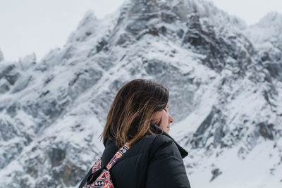 Low angle view of woman standing against snowcapped mountains