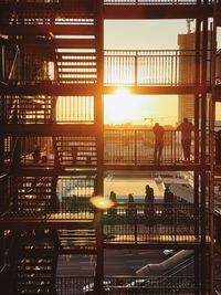 Silhouette people by railing against sky during sunset