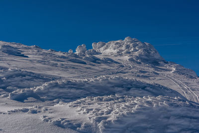 Aerial view of snowcapped mountains against clear blue sky