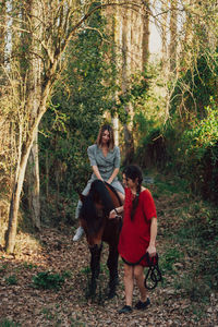 Full length portrait of woman with arms raised in forest