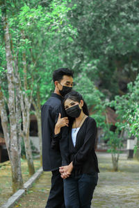 Photo of a couple wearing masks during a pandemic who are on the trail with a view of green trees