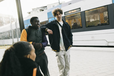 Teenage boy discussing with male friend while waiting at train station