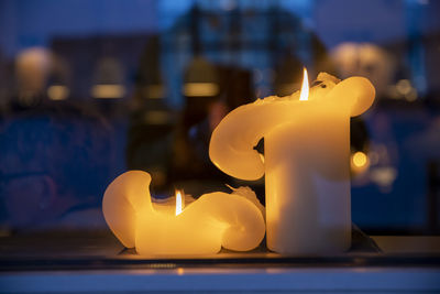 Close-up of illuminated candles on table against building
