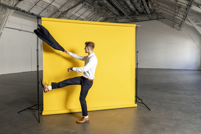 Businessman with blazer dancing in front of backdrop