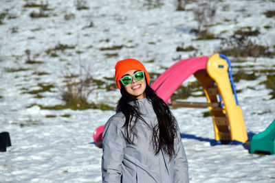 Portrait of smiling young woman standing in snow