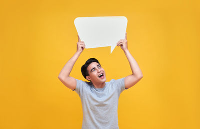 Mid adult man standing against yellow background