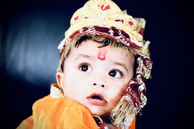Close-up of thoughtful baby boy wearing traditional clothing while sitting on sofa