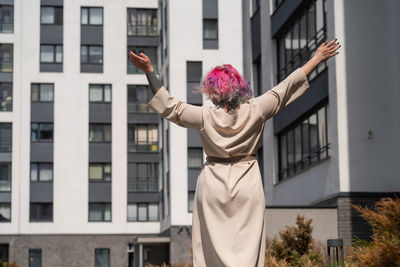 Carefree woman standing against building