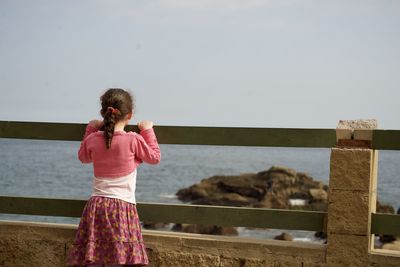 Rear view of woman standing by sea against sky