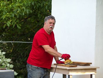 Portrait of man holding red while standing outdoors