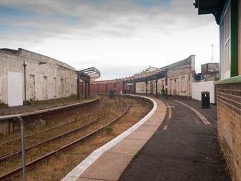 View of empty railroad station against cloudy sky