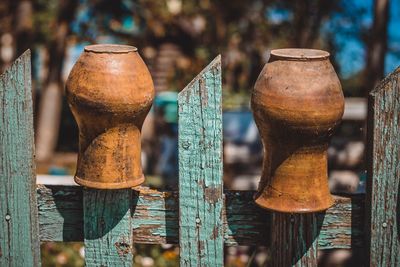 Close-up of abandoned vases on fence