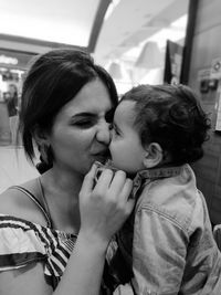 Close-up of boy kissing mother sitting at restaurant