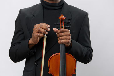 Midsection of man holding violin against white background