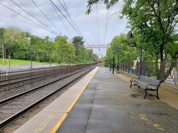 Empty railroad tracks by trees against sky