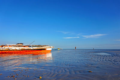 Outrigger boat on beach against sky