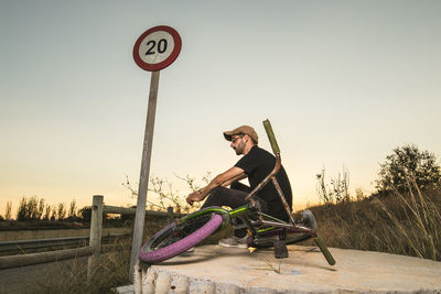 Man sitting on road against clear sky