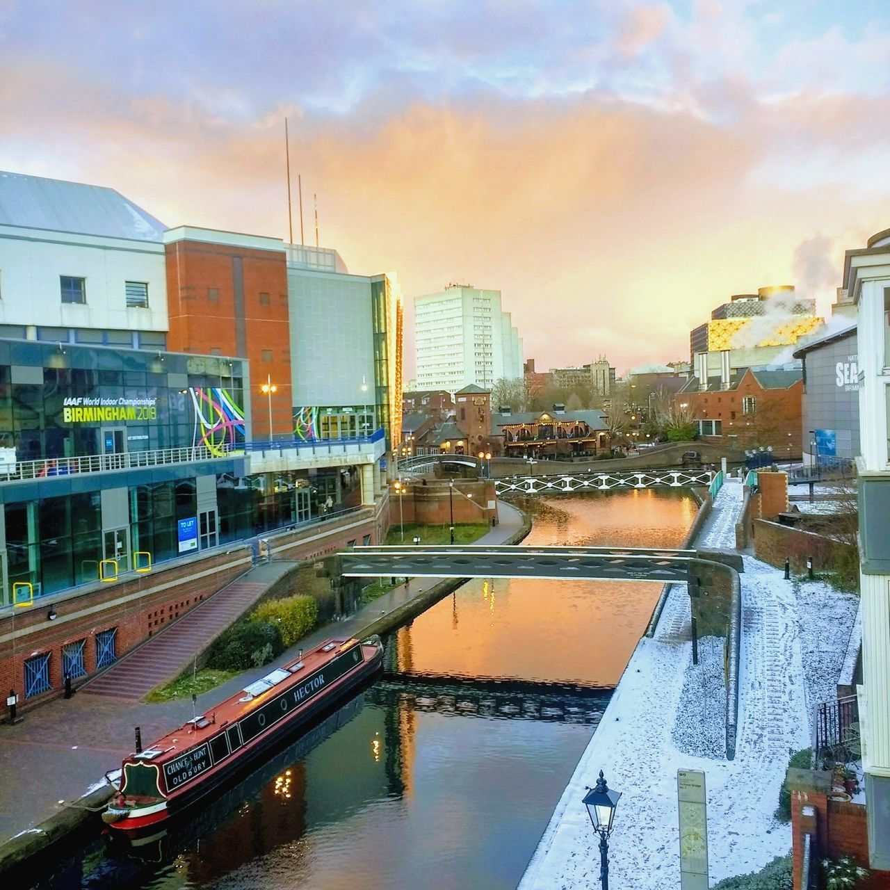 BRIDGE OVER RIVER AMIDST BUILDINGS IN CITY AGAINST SKY