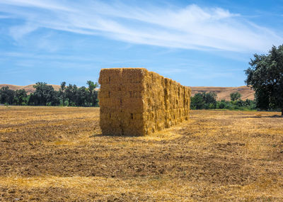 Hay bales on field against sky