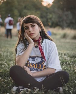 Portrait of young woman sitting on land in park